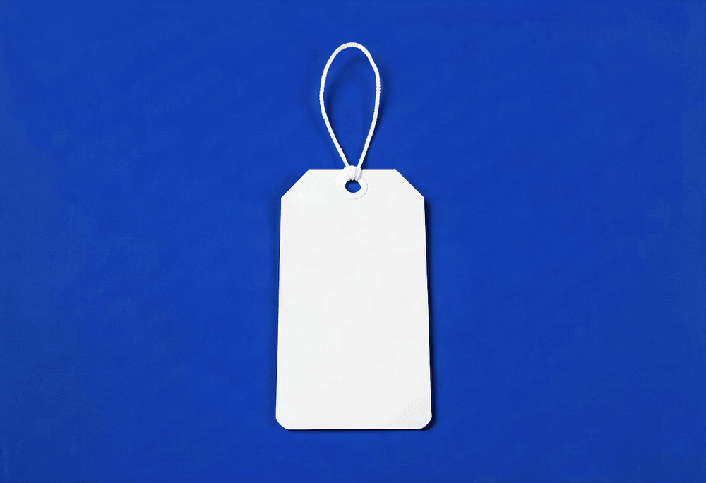 White retail price tag face-down on royal-blue background showing blank back side with no visible price